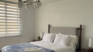 A neatly made bed with a blue and white duvet, a wooden headboard, and bedside lamps.