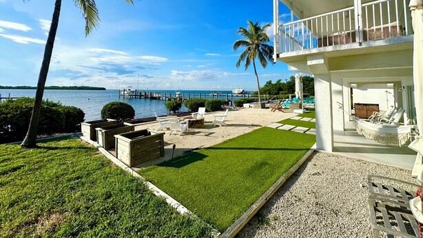 Une propriété située en bord de mer, dotée d’une piscine, de chaises longues et offrant une vue sur l’océan.
