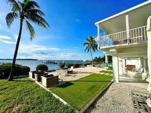Une propriété située en bord de mer, dotée d’une piscine, de chaises longues et offrant une vue sur l’océan.