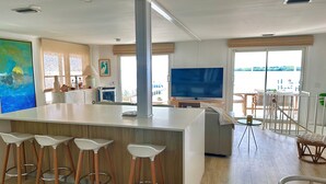 Une cuisine moderne dotée d’un îlot central, de tabourets de bar et d’un grand téléviseur.