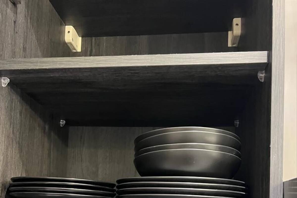Un armari de cuina amb prestatges que contenen plats, bols, tasses i una tetera.