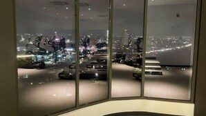 A modern interior with large floor-to-ceiling windows offering a nighttime cityscape view. - Loxwood House (Accra)