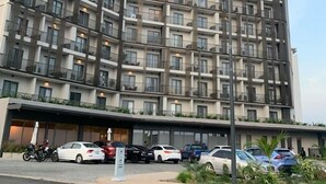A modern multi-story hotel with a uniform facade, balconies, and a covered entrance area with parked cars. - Loxwood House (Accra)