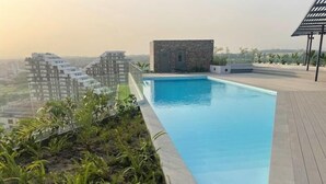 A rooftop pool with a stone wall and a view of surrounding buildings. - Loxwood House (Accra)