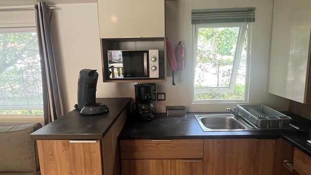 A compact kitchen with a microwave, coffee maker, and sink. - Mobile home rental 8 berths (Parentis-en-Born)