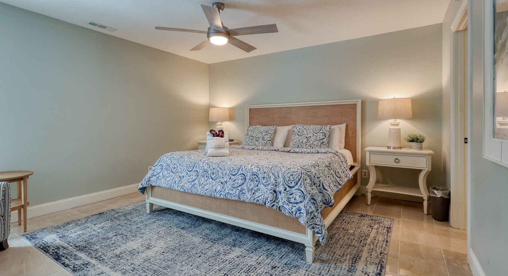 A bedroom with a bed, bedside tables, a ceiling fan, and a nightstand.