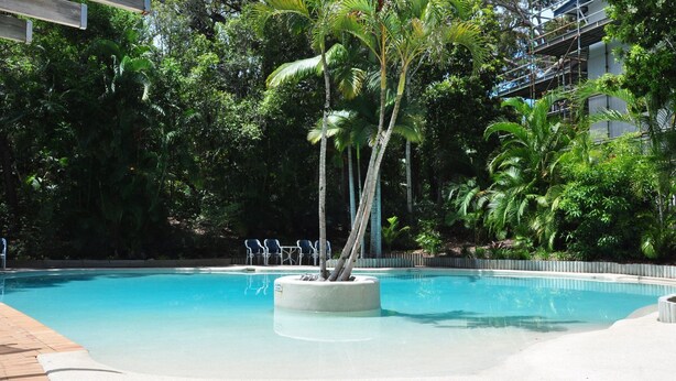 A pool with a circular island, surrounded by palm trees and dense foliage. - Baden 26 - Rainbow Shores (Rainbow Beach)