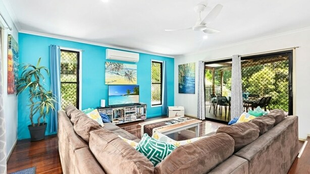 A living room with a blue wall, a large sofa, a coffee table, and a TV.