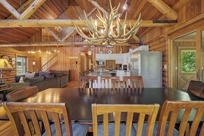 A log cabin interior with a dining area, kitchen, and a staircase leading to another level. - Log Home, game room/hot tub/firepit (Galena)
