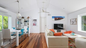 Un salon moderne comprenant un canapé, un téléviseur et un coin repas avec des chaises et une table.