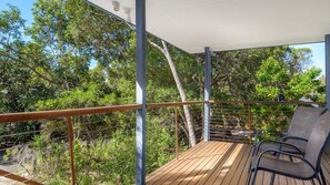 A wooden deck with metal railings, surrounded by dense greenery and trees. - Mortimer - Rainbow Shores (Rainbow Beach)