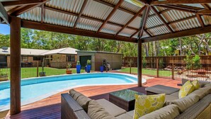 Ein überdachter Pool im Freien mit Holzterrasse und Metalldach.