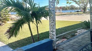 Un patio techado con vista a un césped y palmeras.