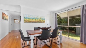 Un comedor con una mesa de madera y cuatro sillas, un cuadro en la pared y un ventanal con cortinas.