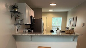 Un coin repas avec une table en marbre, des chaises marron et un plateau décoratif.