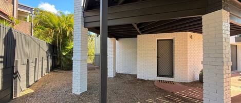 A covered outdoor area with brick pillars, a gravel ground, and a metal fence.