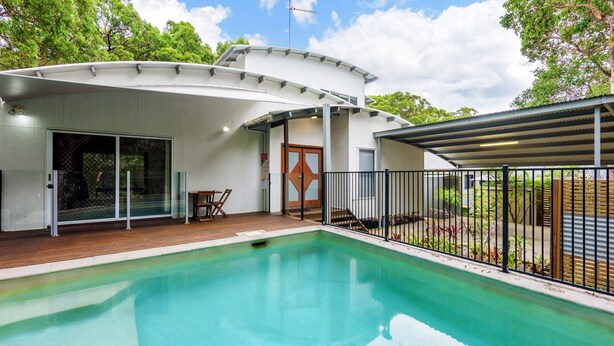 A modern house with a swimming pool, a covered patio, and a fenced garden area.
