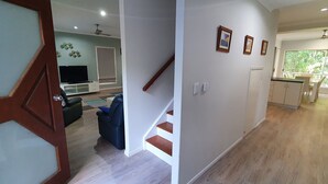 A modern interior with a staircase, a living area with a TV, and a kitchen with a window.