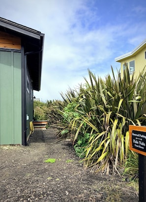 A gravel path leading to a building with a green exterior and a sign indicating reserved parking for a guest house. - Hale Nalu " House of the Waves ": 2-bedroom ocean view cottage in Yachats (Yachats)
