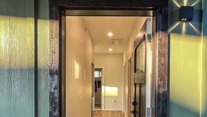 A hotel entrance with a sign reading "Hale Nalu," a hallway with a patterned carpet, and a potted plant.