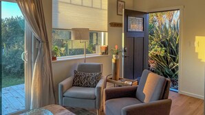 A room with a view of the outdoors, a chair, a small table, and a door leading outside.