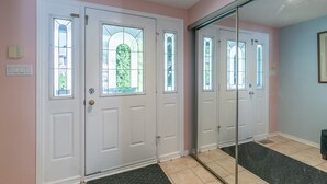 A hallway with three white doors, a glass door, and a large mirror.