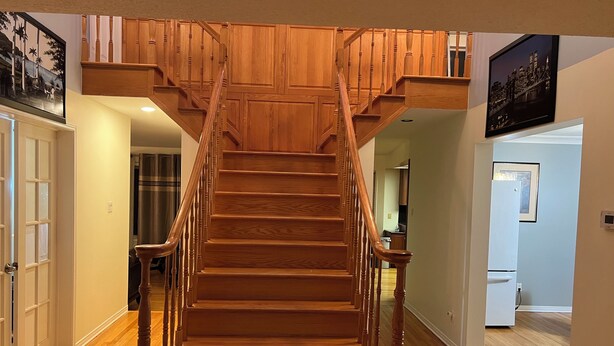 A wooden staircase with a handrail, leading to an upper landing.