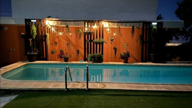 Una piscina con cerramiento de madera y plantas en macetas.