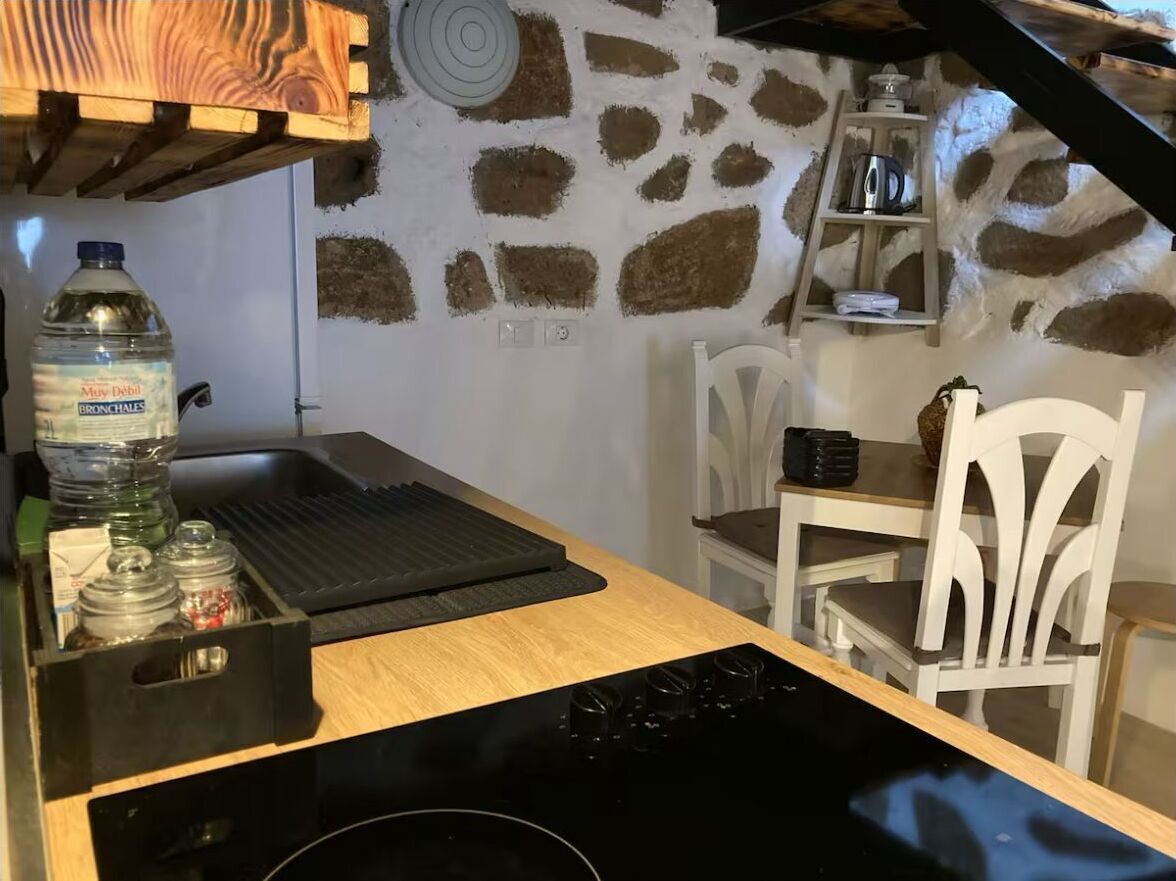 Een keuken met een stenen muur, een houten plafond en witte stoelen.