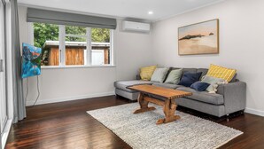 Ein Wohnzimmer mit grauem Sofa, einem Holztisch und einem Bild an der Wand.