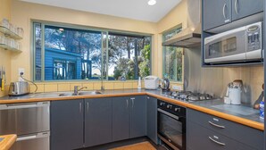 Une cuisine moderne dotée d’une grande fenêtre, d’appareils électroménagers en acier inoxydable et de plans de travail en bois.