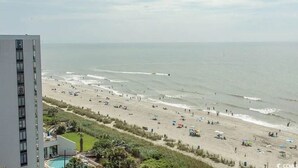 A beach with a pool area and a building in the foreground.