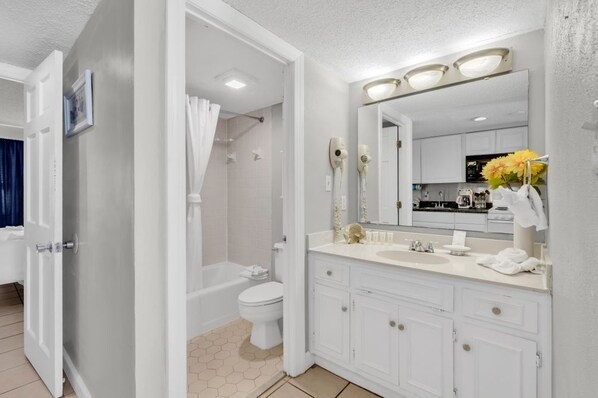 A modern bathroom with a walk-in shower, toilet, and vanity with a large mirror.