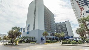 A tall hotel with a modern design, featuring multiple floors and a prominent vertical feature on the facade.