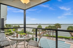 Een balkon met een tafel, stoelen en uitzicht op een waterpartij.