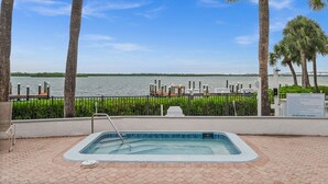 A swimming pool with a view of the water and a dock area. - Bayfront Condo w/ Sunrise Views & Resort Amenities (Marco Island)