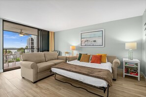 A modern bedroom with a bed, a sofa, and a small table with books.