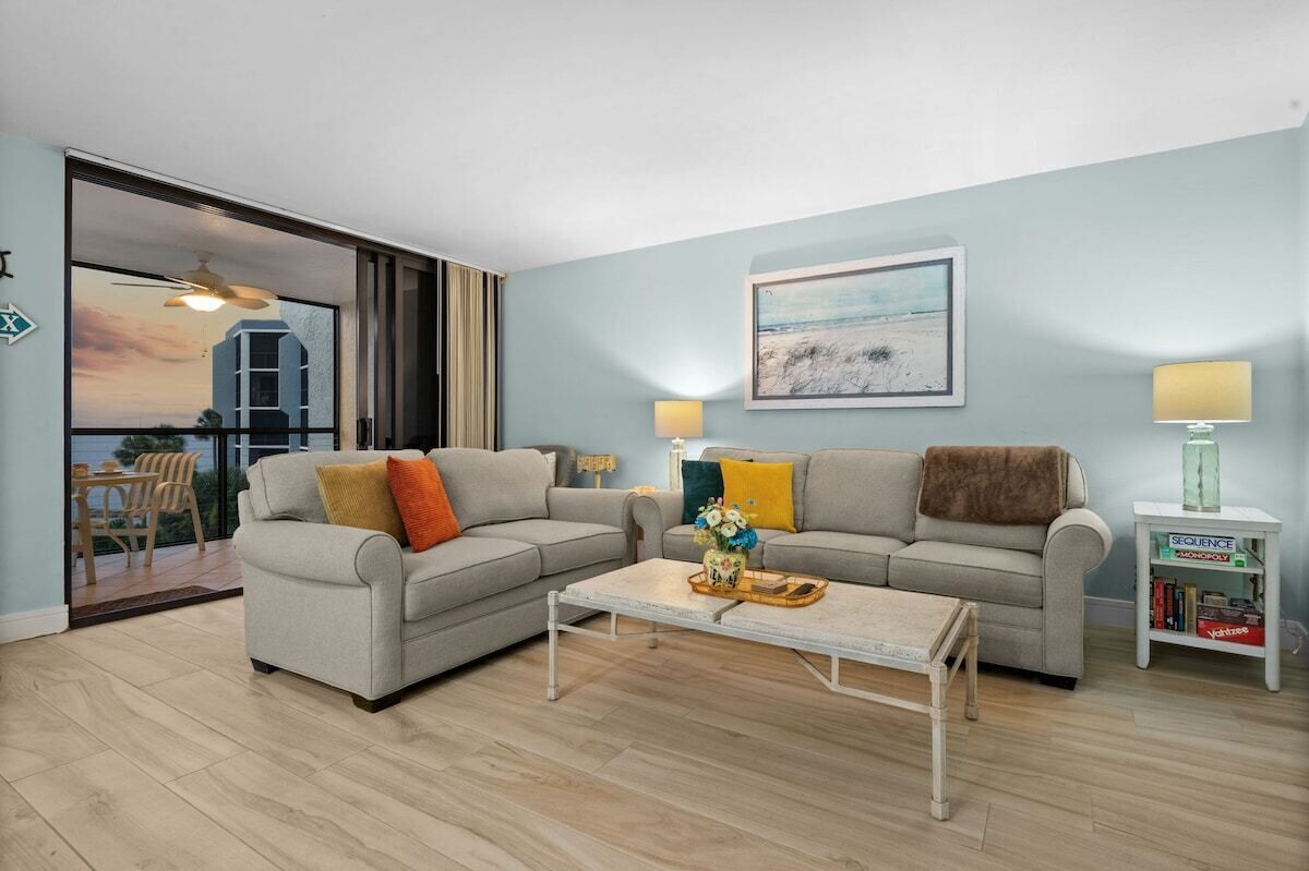 Sala de estar com dois sofás, uma mesa de centro e uma mesinha lateral com livros.