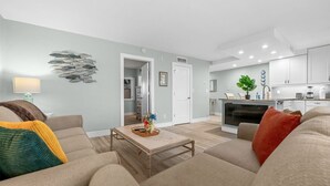 Un salon moderne avec un canapé, une table basse et une cuisine en arrière-plan.