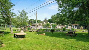 A grassy outdoor area with picnic tables, a wooden bench, and a small shed. - Family and Workation Retreat (Tobyhanna)