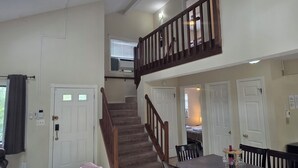 A two-story home with a staircase, a dining area with a table and chairs, and a living room with a couch. - Family and Workation Retreat (Tobyhanna)
