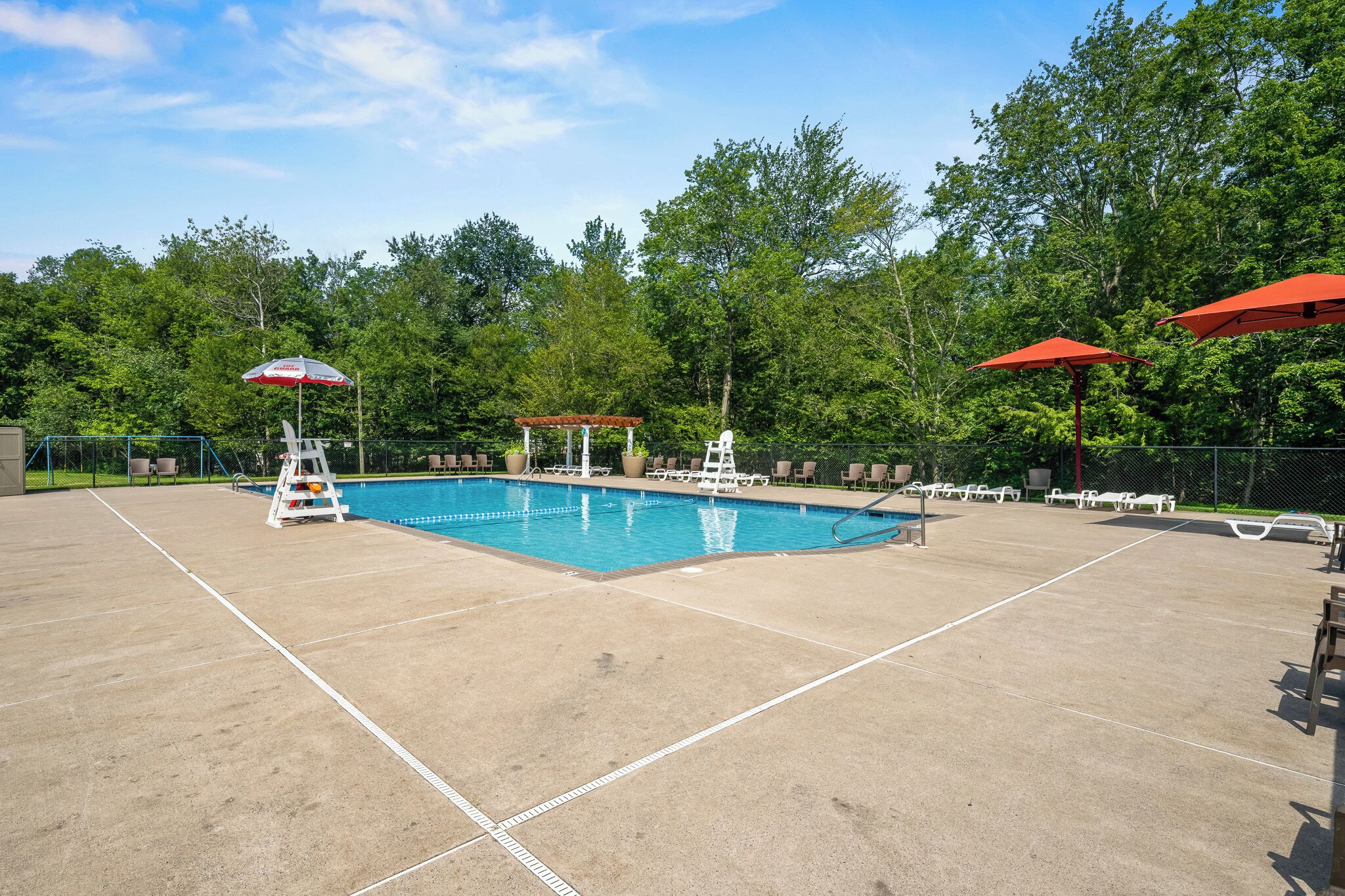 Une piscine équipée d’un poste de surveillance pour le sauveteur, de chaises longues et de parasols.