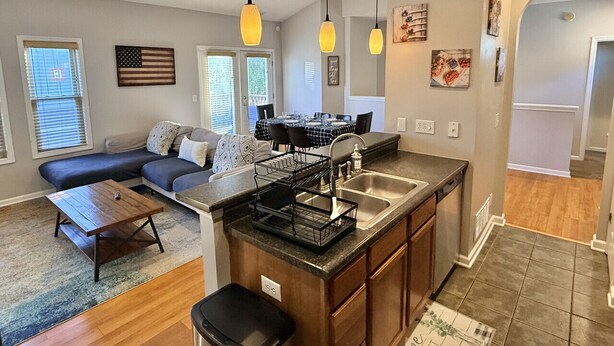 Une cuisine moderne dotée d’un îlot central, un coin repas avec une table et des chaises, et un salon avec un canapé et une table basse.