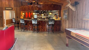 A bar area with wooden walls, a red sofa, and a foosball table.