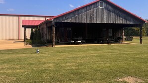 A rustic barn-style building with a red roof and a covered patio area.