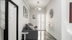 Un pasillo moderno con un sofá gris, piso de mármol y una mesa de vidrio.