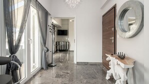 Un pasillo moderno con suelo de mármol, una puerta de madera, un espejo redondo y una mesa de diseño único.