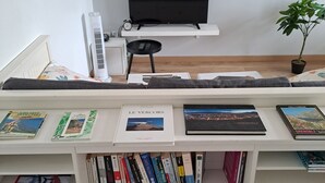 Een woonkamer met een witte entertainmentkast waarop boeken en een flatscreen televisie staan.