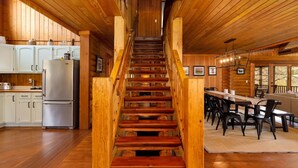 Una escalera de madera que conduce a un comedor con vistas al exterior.