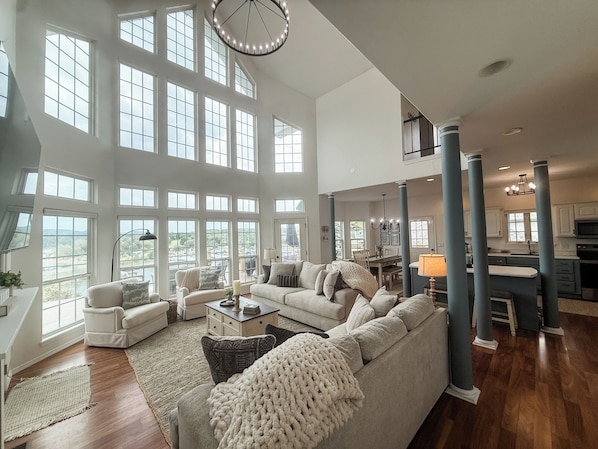 A spacious living room with a large sectional sofa, a dining area, and a kitchen visible through an open layout.